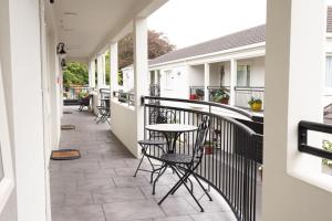 Un patio con sillas y una mesa en el balcón. en Milano Motor Lodge en Christchurch