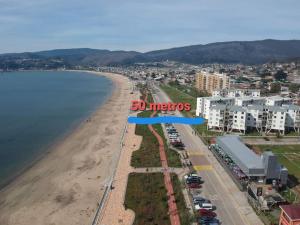 - une vue aérienne sur une plage avec un panneau bleu dans l'établissement Departamento en Dichato, 4 personas frente a la playa, à Dichato