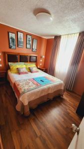 - une chambre avec un lit aux murs orange et du parquet dans l'établissement Departamento en Dichato, 4 personas frente a la playa, à Dichato
