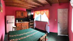 d'une cuisine avec des murs roses, un réfrigérateur et une table. dans l'établissement Hosteria Dharma, à Capilla del Monte