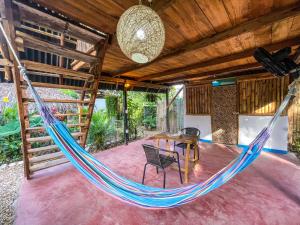 a hammock in a room with a table and chairs at Los Almendros Palomino Hostel in Palomino