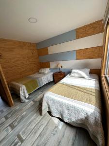 two beds in a room with wooden floors at Cabañas Terra Palafito in Castro