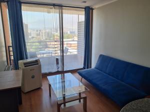 Departamentos Pontoni Manquehue في سانتياغو: غرفة معيشة مع أريكة زرقاء وطاولة زجاجية