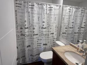Baño con cortina de ducha con escritura en Departamentos Pontoni Manquehue, en Santiago