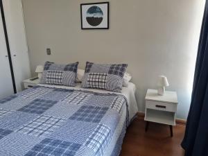a bedroom with a blue and white bed and a night stand at Departamentos Pontoni Manquehue in Santiago