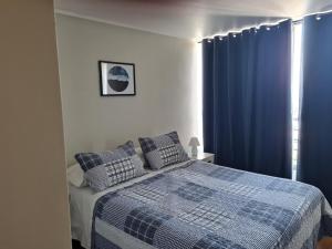 1 dormitorio con 1 cama con cortinas azules en Departamentos Pontoni Manquehue, en Santiago