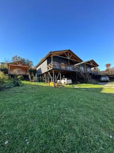 a house with a grass field in front of it at Cabañas Terra Palafito in Castro