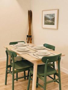 a wooden table with four green chairs around it at The Burrow - Downtown Revelstoke in Revelstoke