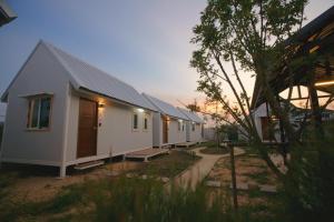 eine Reihe weißer Häuser in einem Hof in der Unterkunft Barn Sampran Resort บ้านสามพรานรีสอร์ท in Nakhon Pathom