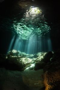 a cave with the light shining through the water at White Grass Ocean Resort & Spa in Tanna Island