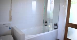 y baño blanco con ducha y aseo. en Discover Booker Bay - Central Coast Family Getaway en Booker Bay