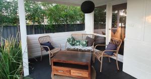 un porche con 2 sillas y una mesa en una casa en Discover Booker Bay - Central Coast Family Getaway, en Booker Bay