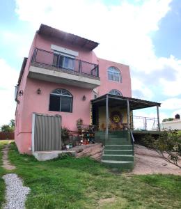 une maison rose avec des escaliers devant elle dans l'établissement Hosteria Dharma, à Capilla del Monte