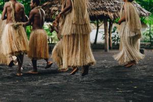 un grupo de mujeres con faldas de hierba caminando en un campo en White Grass Ocean Resort & Spa en Isla de Tanna
