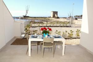 a white table with chairs and flowers on a balcony at Altomare Case Vacanza in Torre Lapillo +9 photos