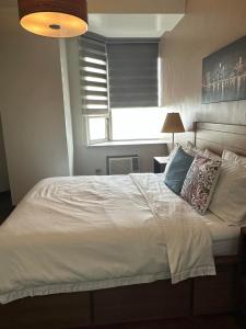 um quarto com uma grande cama branca e uma janela em Suites de Marina Manila with Netflix em Manila