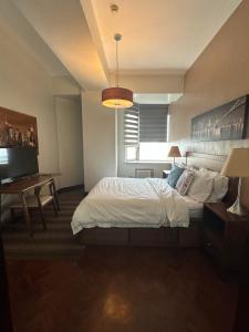 a bedroom with a bed and a desk and a television at Suites de Marina Manila with Netflix in Manila