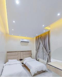Duas camas num quarto com uma janela em شاليه بلاك وايت em Al Harazat