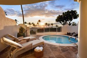 a patio with a swimming pool and chairs next to a swimming pool at The Villas at Fairmont Kea Lani in Wailea