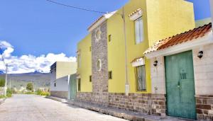 un edificio amarillo con puertas verdes en una calle en Chuklla, en Yanque