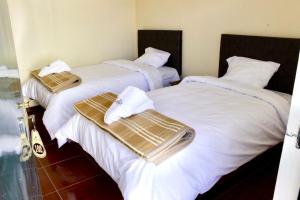 2 Betten mit weißer Bettwäsche und Handtüchern darauf in der Unterkunft Chuklla in Yanque