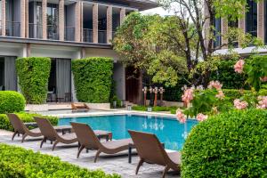 a courtyard with a swimming pool with chairs and flowers at Villa Deva Resort & Hotel Bangkok in Bangkok