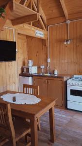 a wooden kitchen with a table and a stove at Cabaña Aiken in Esquel