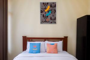 uma cama com duas almofadas e uma fotografia na parede em Sans Hotel Kumbang Yogyakarta by RedDoorz em Yogyakarta