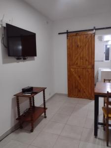 a room with a tv and a table and a door at Lomas del Mirador in San Fernando del Valle de Catamarca