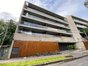 ein Apartmenthaus mit einem Holzzaun davor in der Unterkunft Departamento céntrico a estrenar - Con piscina y cochera in Tigre