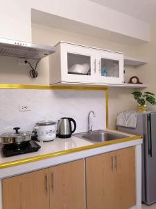 ドゥマゲテにあるR&R Cozy 2BR Marina Dumagueteのキッチン(シンク、コンロ、キャビネット付)