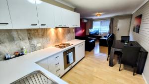 a kitchen with white cabinets and a living room at 5 min walk to City Center in Toowoomba