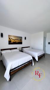 two beds in a room with white walls at Red Flamboyan Guesthouse and Restaurant in Rincon
