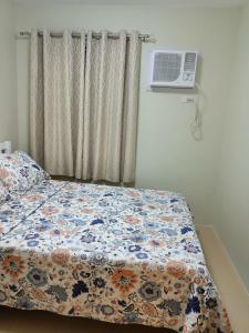 ドゥマゲテにあるR&R Cozy 2BR Marina Dumagueteのベッドルーム1室(花柄の掛け布団、窓付)