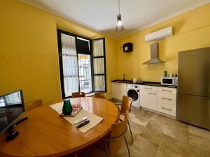 Il comprend une cuisine équipée d'une table en bois et d'un réfrigérateur. dans l'établissement Apartamento con Encanto próximo Alameda Hercules, à Séville