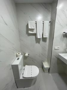 a white bathroom with a toilet and a sink at Hotel Bradomin in Villanueva de Arosa