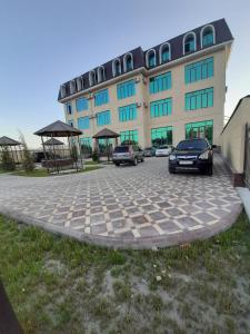 dwa samochody zaparkowane na parkingu przed budynkiem w obiekcie Rudaki Hotel in Panjakent w mieście Panjakent
