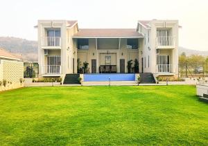 a large house with a large lawn in front of it at Isola Luxury Farm Suites in Nashik