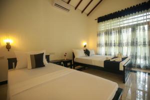 a bedroom with two beds and a window at Riverview Cabana Tissamaharama in Tissamaharama