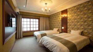 a hotel room with two beds and a chandelier at Ryokan Kiraku in Beppu