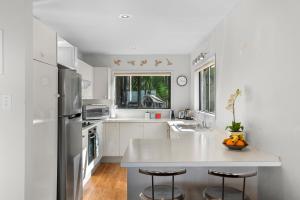uma cozinha branca com um balcão e um frigorífico em Simply Fabulous - Mangawhai Heads Holiday Home em Mangawhai