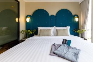 a bedroom with a large white bed with a blue headboard at Benjarong Hotel Bangkok in Ban Zong Katiam