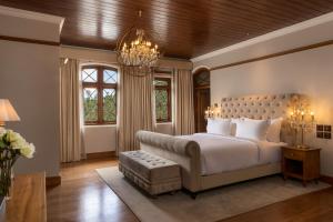a bedroom with a large bed and a chandelier at The Bellwood Manor in Nuwara Eliya