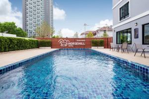 a swimming pool with a red fence next to a building at Horsehill Hotel Sriracha in Si Racha