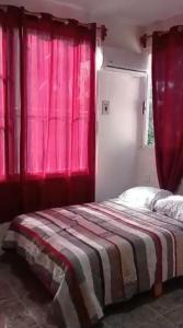 a bedroom with a bed with pink curtains and a window at Departamentos La Angosta in Acapulco