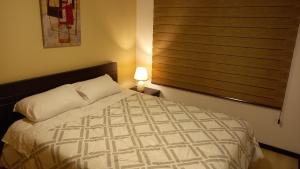 a bedroom with a bed with a window and a lamp at Departamento 2B en Condominio La Victoria in Cuenca