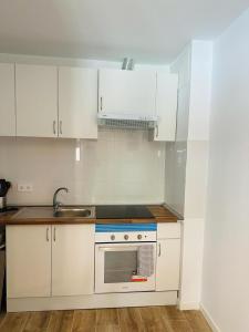 a kitchen with white cabinets and a sink and a stove at MINI ESTUDIOS SANSE in San Sebastián de los Reyes
