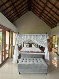 Munduk Sari Resort في موندوك: غرفة نوم مع سرير مظلة وأريكة