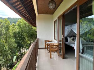 Balcón con cama, mesa y sillas en Munduk Sari Resort, en Munduk