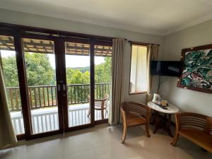 a living room with a balcony with sliding glass doors at Munduk Sari Resort in Munduk